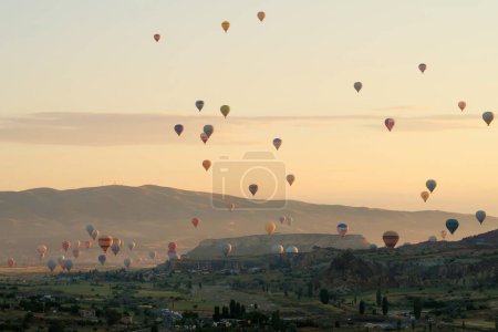 Many colorful hot air balloons over the landscape of the Red Valley, Rose Valley at sunrise, close to Goreme, Cavusin, Cappadocia, Turkey 2022