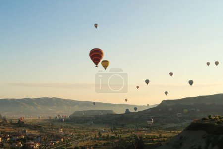 Colorful hot air balloons flying over the landscape of the Red Valley, Rose Valley, close to Goreme, Cavusin, Cappadocia, Turkey 2022