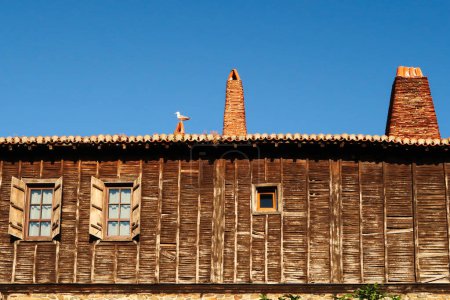 Gaviota sentado en el techo de una casa de madera tradicional en el casco antiguo de Sozopol, Sosopol una ciudad costera en el mar negro, Bulgaria 2022
