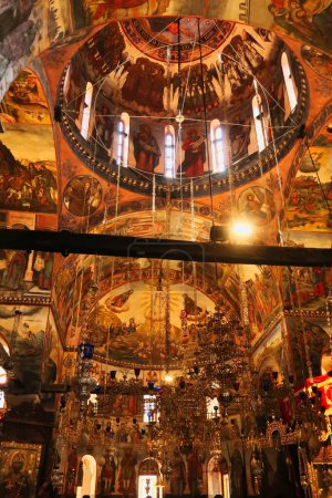 The elaborate decoration inside the Church St., Saint Archangels Michael and Gabriel at the Bachkovo Monastery, colorful frescos, ceiling, wall paintings and golden chandeliers, close to Plovdiv, Bulgaria 2022