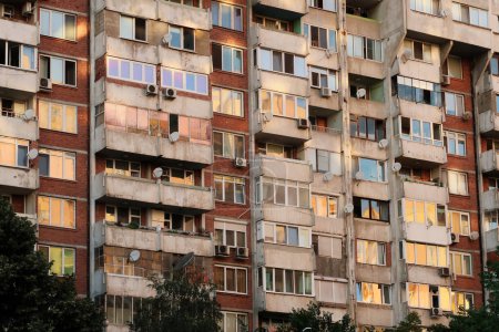 Le coucher de soleil se reflète dans les nombreuses fenêtres d'un panneau de béton, socialiste, brutaliste, multi-étages, gratte-ciel, immeuble, bâtiment, orange, jaune, rose reflet, Sofia, Bulgarie 2022