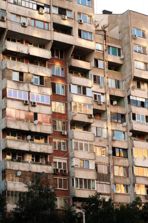 Le coucher de soleil se reflète en orange, jaune, rose dans les nombreuses fenêtres d'un panneau de béton, socialiste, brutaliste, multi-étages, grande hauteur, immeuble, Sofia, Bulgarie 2022