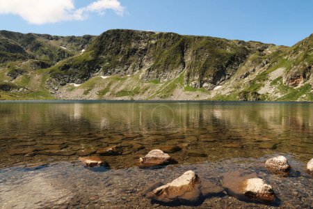 The mountains are reflecting on the smooth surface of the Kidney, Babreka Lake, one of the Seven Rila Lakes, situated on a plateau in the Rila National Park, close to Sofia, Bulgaria 2022