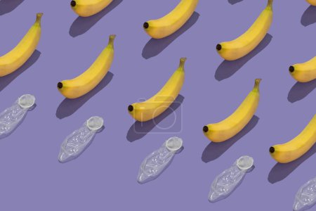 Foto de Patrón con plátanos y condones sobre fondo púrpura. Concepto de sexo seguro. - Imagen libre de derechos