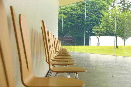 Photo for Wooden chairs in a row looking out of a window. Contemplation space, empty chairs waiting to be occupied, ideal to represent the idea of meeting people, contemplation or new courses in classrooms - Royalty Free Image