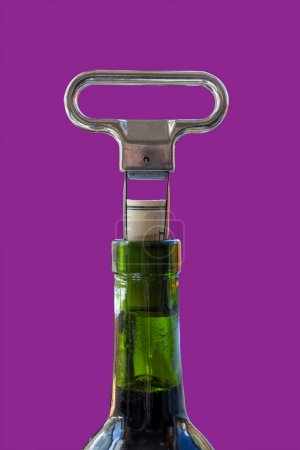 Two prong cork puller and cork halfway pulled from green wine bottle