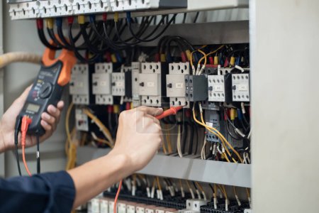 Photo for Electrician engineer work tester measuring voltage and current of power electric line in electical cabinet control , concept check the operation of the electrical system . - Royalty Free Image