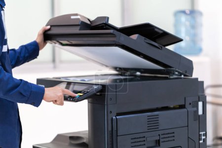 Téléchargez les photos : Bouton de presse d'homme d'affaires sur le panneau du réseau de photocopieur d'imprimante, travaillant sur des photocopies dans le concept de bureau, imprimante est équipement d'outil d'employé de bureau pour numériser et copier le papier. - en image libre de droit
