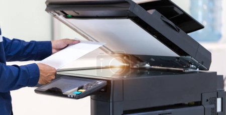 Foto de El hombre de negocios presiona el botón en el panel de la red de fotocopiadoras de la impresora, trabajando en fotocopias en el concepto de oficina, la impresora es el equipo de herramientas del trabajador de oficina para escanear y copiar papel. - Imagen libre de derechos