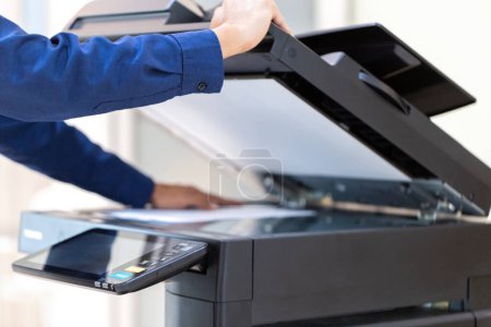 Téléchargez les photos : Bouton de presse d'homme d'affaires sur le panneau du réseau de photocopieur d'imprimante, travaillant sur des photocopies dans le concept de bureau, imprimante est équipement d'outil d'employé de bureau pour numériser et copier le papier. - en image libre de droit