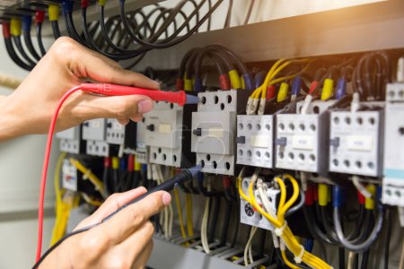 Foto de Electricistas manos prueba corriente eléctrica en el panel de control. - Imagen libre de derechos