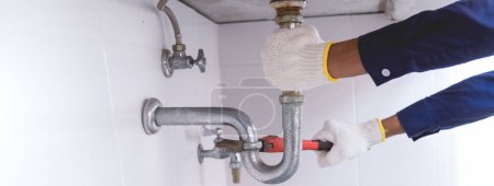 Photo for Plumber fixing white sink pipe with adjustable wrench. - Royalty Free Image