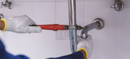 Téléchargez les photos : Plombier fixation tuyau d'évier blanc avec clé réglable. - en image libre de droit