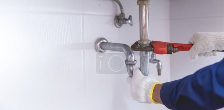 Photo for Plumber fixing white sink pipe with adjustable wrench. - Royalty Free Image