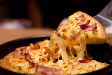 Foto de Rebanada de pizza caliente con queso derretido en una mesa en el restaurante pizza comida italiana. - Imagen libre de derechos