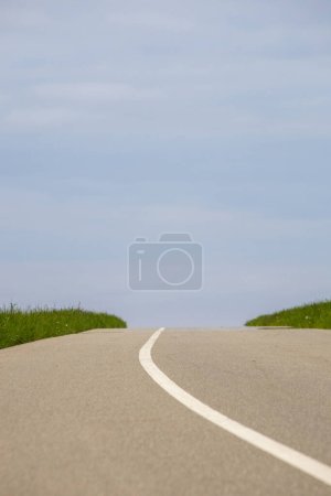 Téléchargez les photos : Route asphaltée avec herbe verte et ciel bleu en arrière-plan. - en image libre de droit