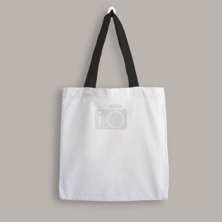 Photo for White blank cotton eco tote bag with black straps, design mockup. Shopping bag hanging on wall. - Royalty Free Image
