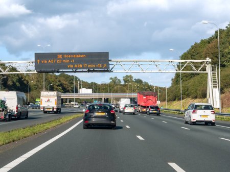 Photo for UTRECHT, NETHERLANDS - OCT 15, 2021: Traffic and overhead gantry displaying electronic information about travel time, motorway A27 between Utrecht and Hilversum - Royalty Free Image