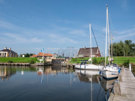 Photo for WORKUM, NETHERLANDS - SEP 14, 2021: View of lock Zeesluis and jetty with sailboats from Het Zool canal, Workum, Friesland - Royalty Free Image