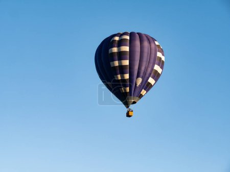 Téléchargez les photos : OOTMARSUM, PAYS-BAS - 24 OCT 2021 : Montgolfière bleu foncé avec des personnes dans le panier volant dans l'air et ciel bleu sans nuages - en image libre de droit