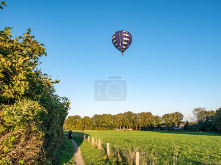 Foto de OOTMARSUM, PAÍSES BAJOS - 24 OCT 2021: Globo aerostático volando sobre prados de campo cerca de Ootmarsum en otoño, Overijssel - Imagen libre de derechos