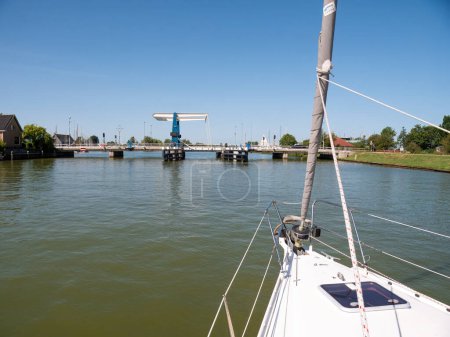 Photo for WARNS, NETHERLANDS - JUL 7, 2023: Sailboat approaching bridge waiting for opening - 1/4, Warnsebrug over Johan Frisokanaal channel in Friesland, Netherlands - Royalty Free Image