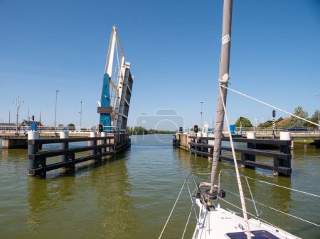 Photo for WARNS, NETHERLANDS - JUL 7, 2023: Sailboat approaching bridge waiting for opening - 4/4, Warnsebrug bridge over Johan Frisokanaal channel in Friesland, Netherlands - Royalty Free Image
