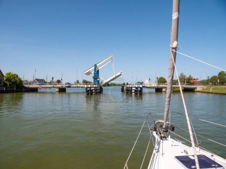 Photo for WARNS, NETHERLANDS - JUL 7, 2023: Sailboat approaching bridge waiting for opening - 2/4, Warnsebrug bridge over Johan Frisokanaal channel in Friesland, Netherlands - Royalty Free Image