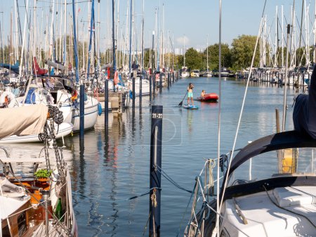Photo for MAKKUM, NETHERLANDS - AUG 12, 2023: Marina Makkum with many sailboats and playing children, Makkum, Friesland, Netherlands - Royalty Free Image