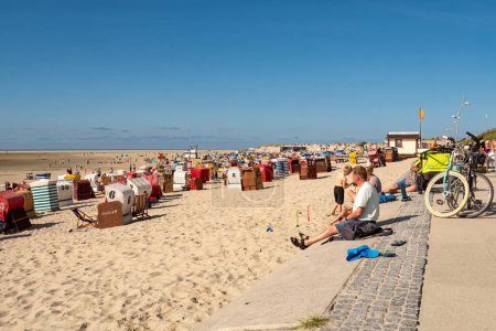 Téléchargez les photos : Borkum, Allemagne - 16 août 2023 : Les gens assis et relaxants sur la promenade de la plage de l'île de Borkum, Frise orientale, Basse-Saxe, Allemagne - en image libre de droit