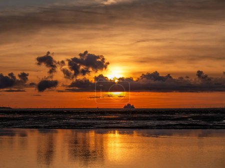 View from Amrum over Wadden Sea at sunrise with ferry boat, North Frisia, Schleswig-Holstein, Germany
