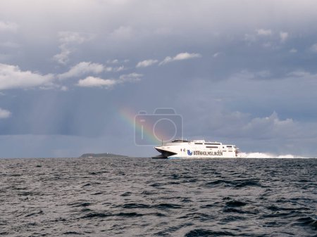 Foto de Kattegat, Dinamarca - 23 / 09 / 2023: Transbordador de alta velocidad que cruza Kattegat con arcoíris y nubes de lluvia ominosas sobre la isla de Hjelm - Imagen libre de derechos