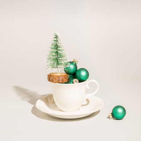 Foto de Copa blanca con árbol de Navidad y burbujas verdes en la mesa. Hora del chocolate caliente o del café. Concepto de vacaciones. - Imagen libre de derechos
