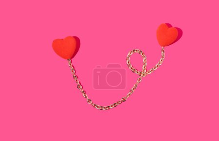 Foto de Creative valentines or romantic concept, two connected hearts with gold chain on pink background. Minimal love concept. - Imagen libre de derechos