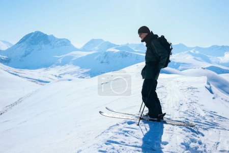 Photo for Professional extreme downhill skier stand on top of mountain look down on fresh powder snow. Man with skis and in waterproof gear on top of ski touring summit - Royalty Free Image