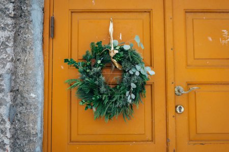 Photo for Beautiful entrance to scandinavian style house with wooden door and christmas wreath. Homemade diy xmas decoration. Winter city doors and landscape. Inspiring winter ornaments and nordic lifestyle - Royalty Free Image