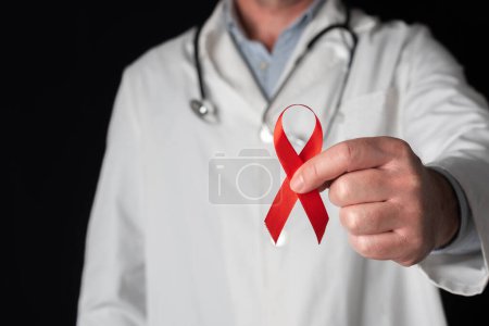 Téléchargez les photos : Docteur montrant un ruban rouge, symbole de la Journée mondiale du sida. Soutien du personnel de santé aux personnes atteintes du VIH. Prévention et lutte contre le virus du sida - en image libre de droit