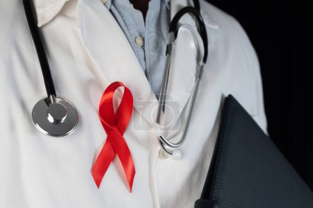 Téléchargez les photos : Gros plan d'un médecin portant un ruban rouge sur sa poitrine, symbole de la Journée mondiale du sida. Soutien du personnel de santé aux personnes atteintes du VIH. Prévention et lutte contre le virus du sida - en image libre de droit