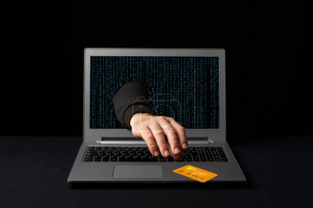 Foto de Un cibercriminal que llega a través de una computadora portátil para robar la tarjeta de crédito de un comprador en línea. Estafas en Internet - Imagen libre de derechos