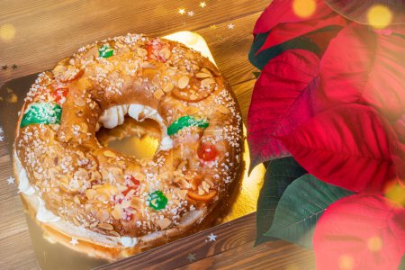 Téléchargez les photos : Gâteau à l'épiphanie "Roscon de Reyes" avec un poinsettia rouge. Dessert typiquement espagnol mangé le jour des Trois Sages à Noël - en image libre de droit