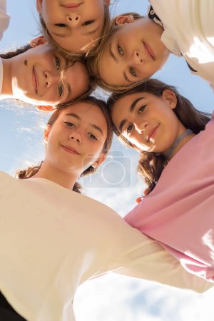 Photo for Five friends huddled in a circle, looking at the camera and smiling. Friendship and unity among girls. Friends forever. Adolescence and puberty - Royalty Free Image