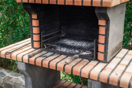 Foto de Barbacoa de ladrillo con carbón encendido lista para asar carne. Día de barbacoa en el jardín con amigos - Imagen libre de derechos