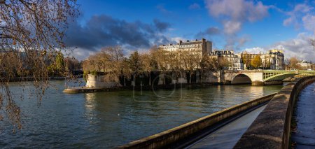 Photo for Stunning autumn panoramic view of the Seine embankment at island of Saint-Louis and the Pont de Sully bridge in bright side sunlight in the historic center of Paris. - Royalty Free Image