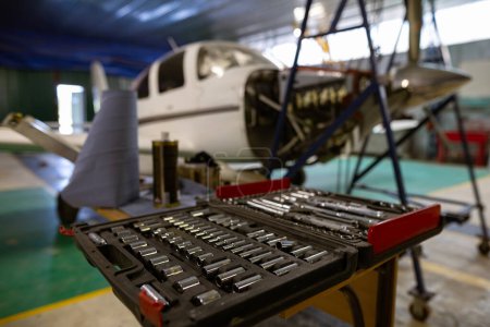 Foto de El hangar es un taller de reparación de automóviles para pequeñas empresas. Conjunto de herramientas de mecánico automático multifuncional. Aviones monomotores ligeros, que necesitan reparación del motor. - Imagen libre de derechos