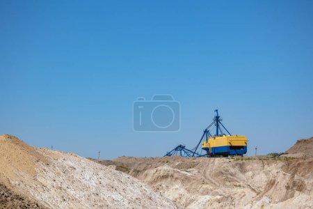 Photo for Quarry extraction porcelain clay(kaolin) and quartz sand in the open pit mine. Powerful industrial walking excavator on the site. - Royalty Free Image