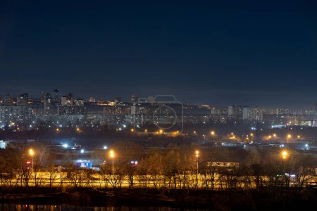 Nachtbild der Großstadt. Helles, buntes Licht auf leeren Straßen. Mehrfamilienhäuser im Stadtgebiet. Kiew Ende März 2024. Ukraine.