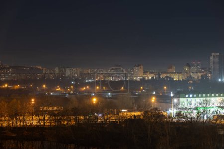Nachtbild der Großstadt. Helles, buntes Licht auf leeren Straßen. Mehrfamilienhäuser im Stadtgebiet. Kiew Ende März 2024. Ukraine.