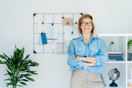 Photo for Smiling middle aged businesswoman near grid mood board with pinned work-life balance wheel diagram in her work space. Finding Balance in Your Life. Life planning. Coaching tools. Selective focus. - Royalty Free Image