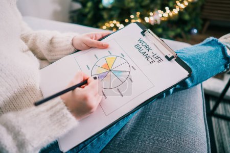 Photo for Woman drawing work-life balance wheel sitting on the sofa at home. Self-reflection and life planning for next new year. Personal Year review. Coaching tools. Finding Balance in Life. Selective focus - Royalty Free Image