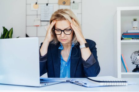 Shocked 50s mature businesswoman, middle-aged experienced female looking at documents in office. Accounting report. Frustrated worried face expression emotion feelings problem perception reaction